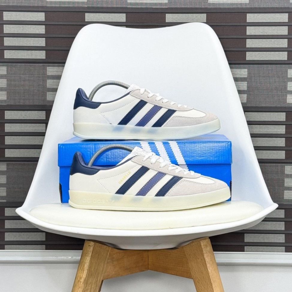 Adidas Gazelle Indoor sneakers in the 'White Preloved Ink' colorway, featuring a white leather upper, blue suede details, and a translucent gum rubber outsole